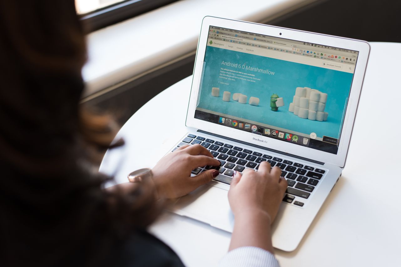 Businesswoman working on a laptop with the Android 6.0 Marshmallow webpage open.